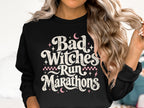 Black sweatshirt with text "Bad Witches Run Marathons" and moon and star graphics.