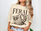 T-shirt with "FERAL" text and a raccoon wearing sunglasses.