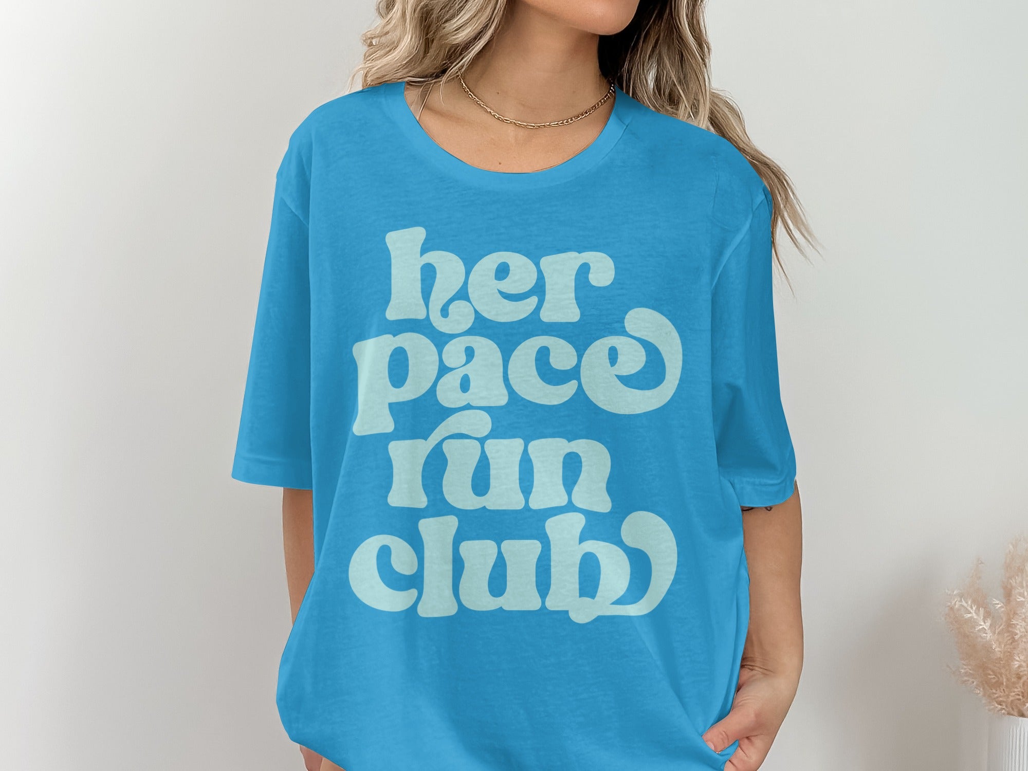 Blue t-shirt with light blue text reading "her pace run club".