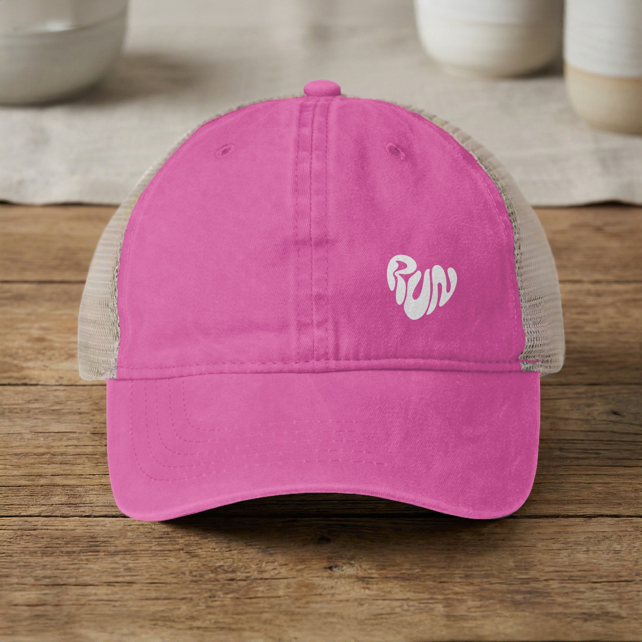 Pink trucker hat with white "run" heart graphic on the front.