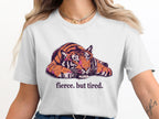 White t-shirt with a graphic of a tiger resting and the text "fierce. but tired."