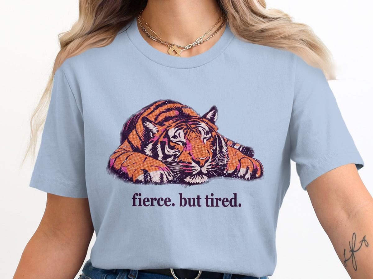 Light blue t-shirt with a graphic of a tired tiger and the text "fierce. but tired."