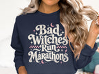 Navy sweatshirt with distressed text "Bad Witches Run Marathons" and celestial accents.