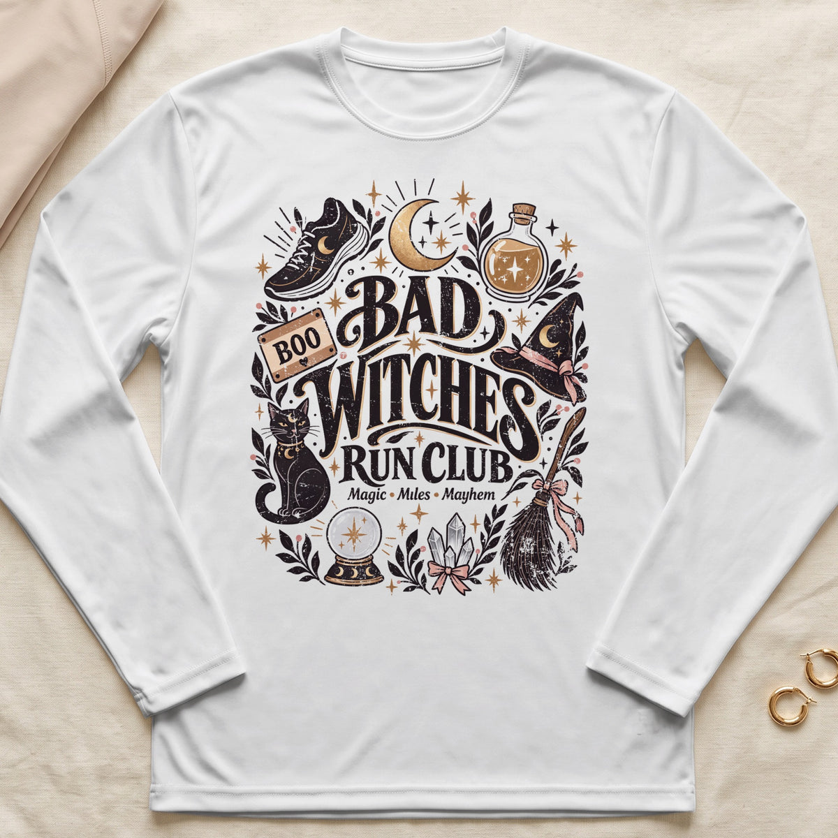 White long sleeve shirt with "Bad Witches Run Club" graphic featuring a cat, moon, and running shoe.
