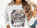 White sweatshirt with "Bad Witches Run Club" graphic featuring a shoe, potion, cat, and broom.