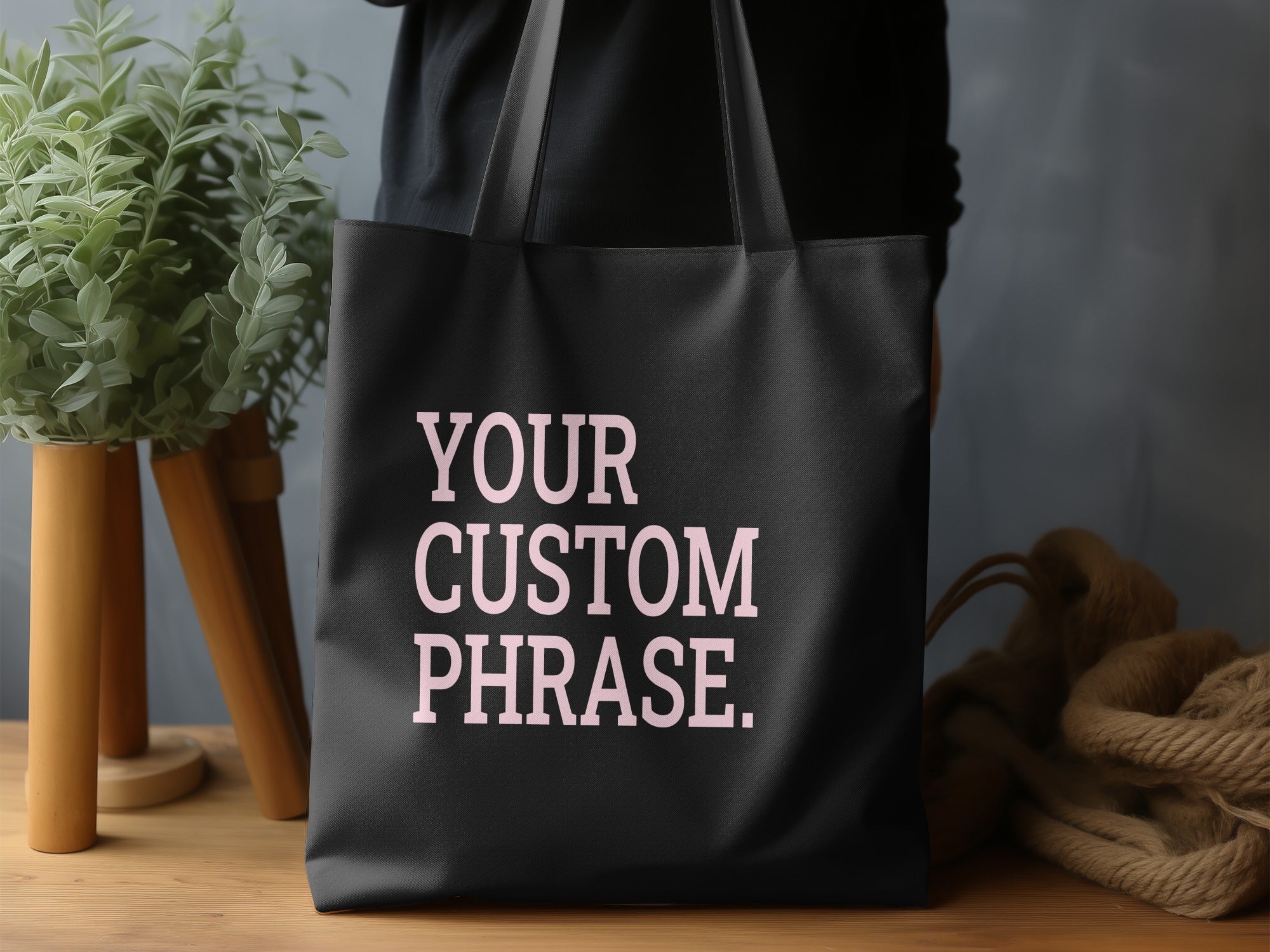 Black tote bag with pink text reading "YOUR CUSTOM PHRASE."