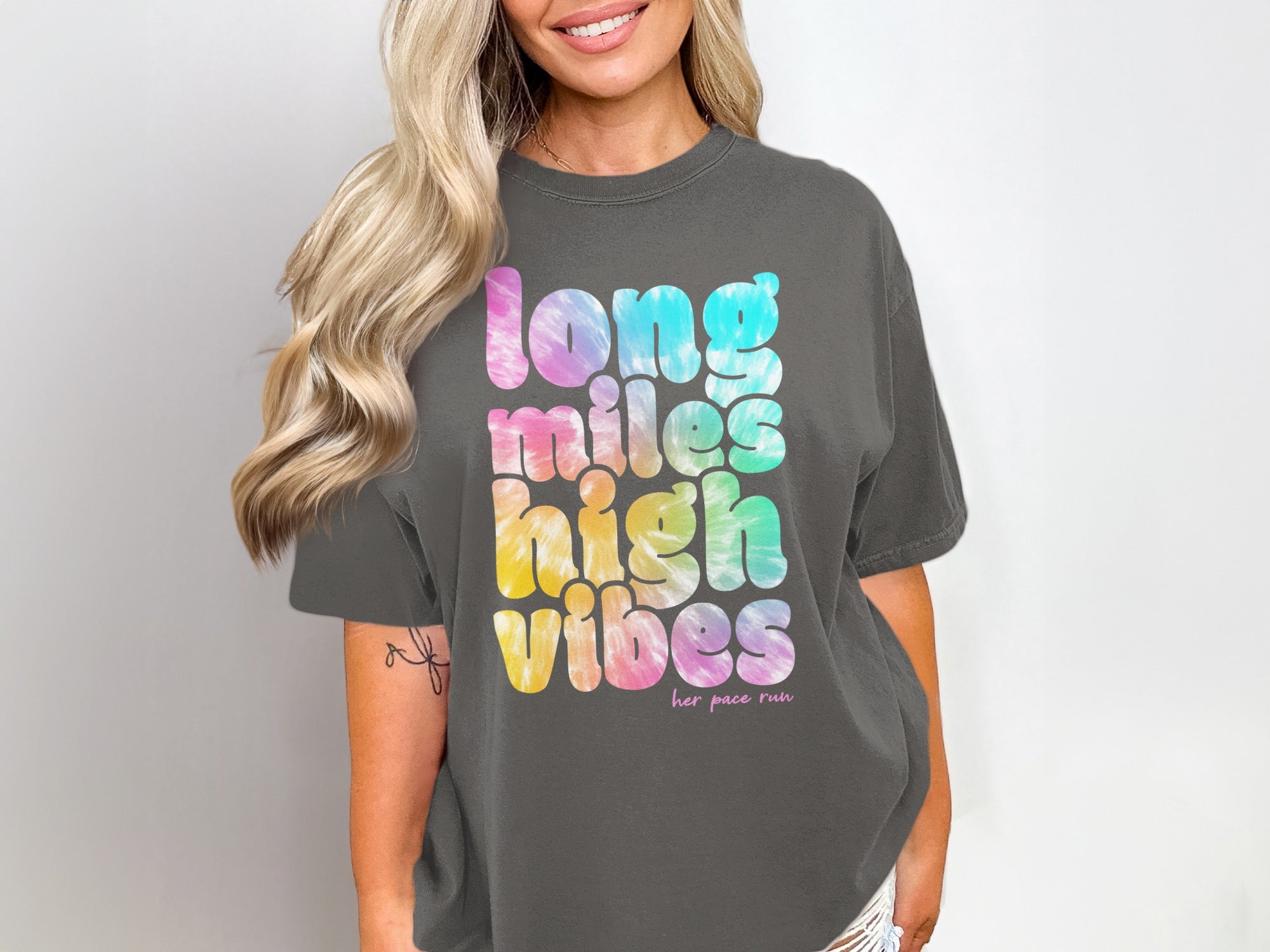 Dark grey t-shirt with tie-dye text reading "long miles high vibes her pace run".
