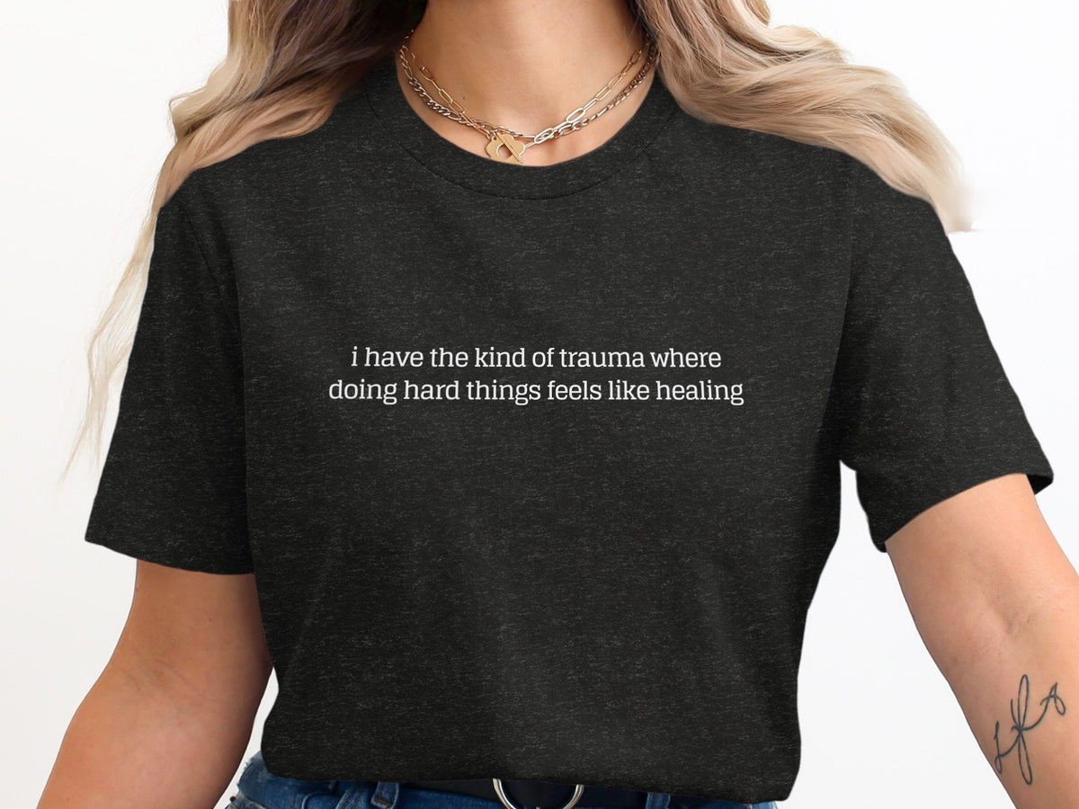 Dark t-shirt with text "i have the kind of trauma where doing hard things feels like healing".