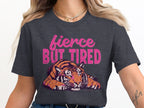 Dark grey t-shirt with "fierce BUT TIRED" text and a stylized tiger graphic.