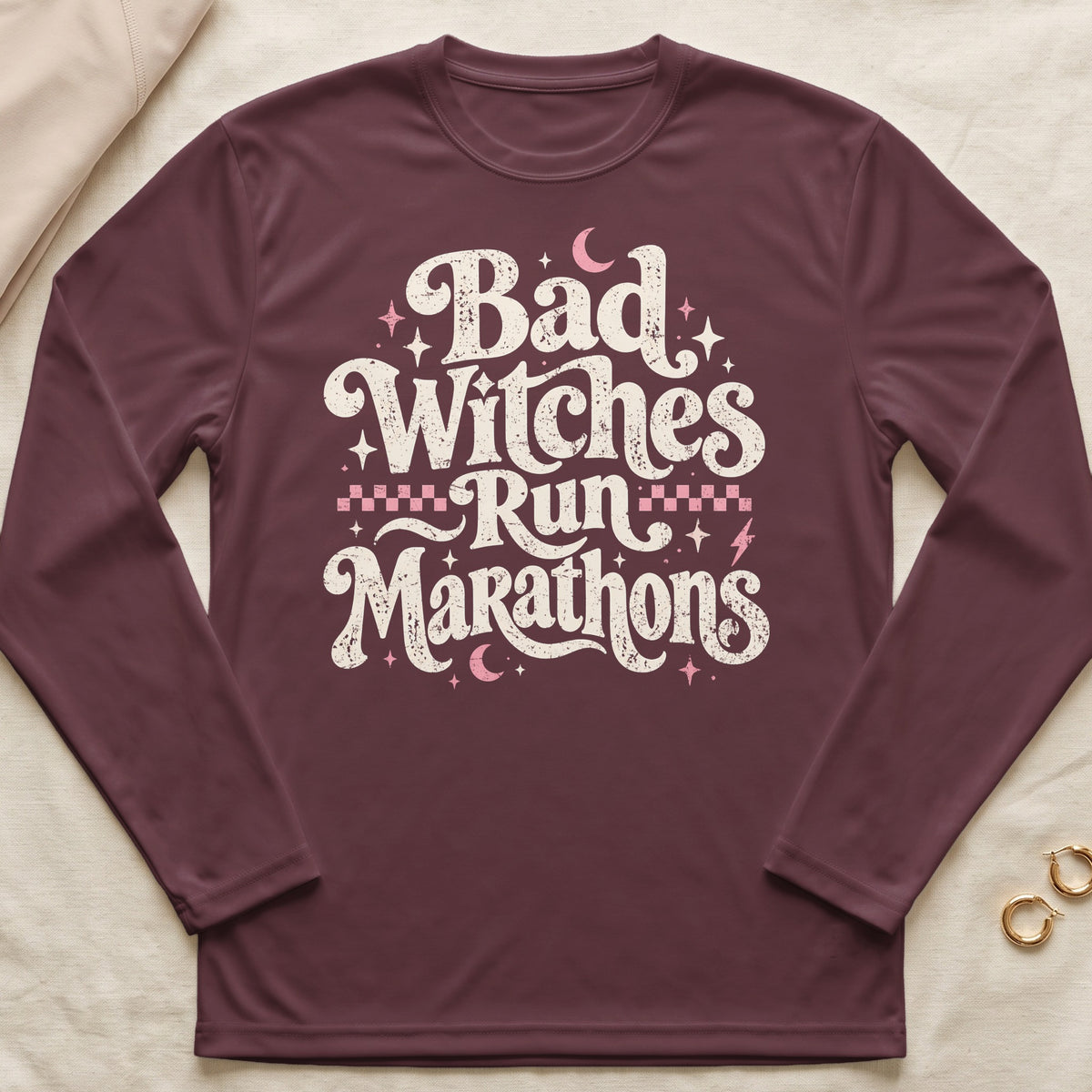 Maroon long-sleeve shirt with "Bad Witches Run Marathons" graphic and celestial accents.