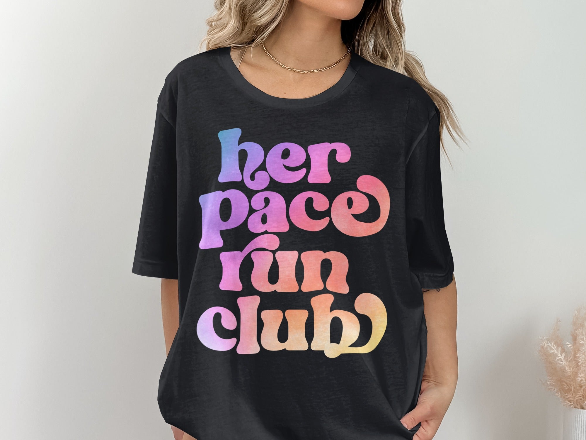 Black t-shirt with colorful "her pace run club" text graphic.