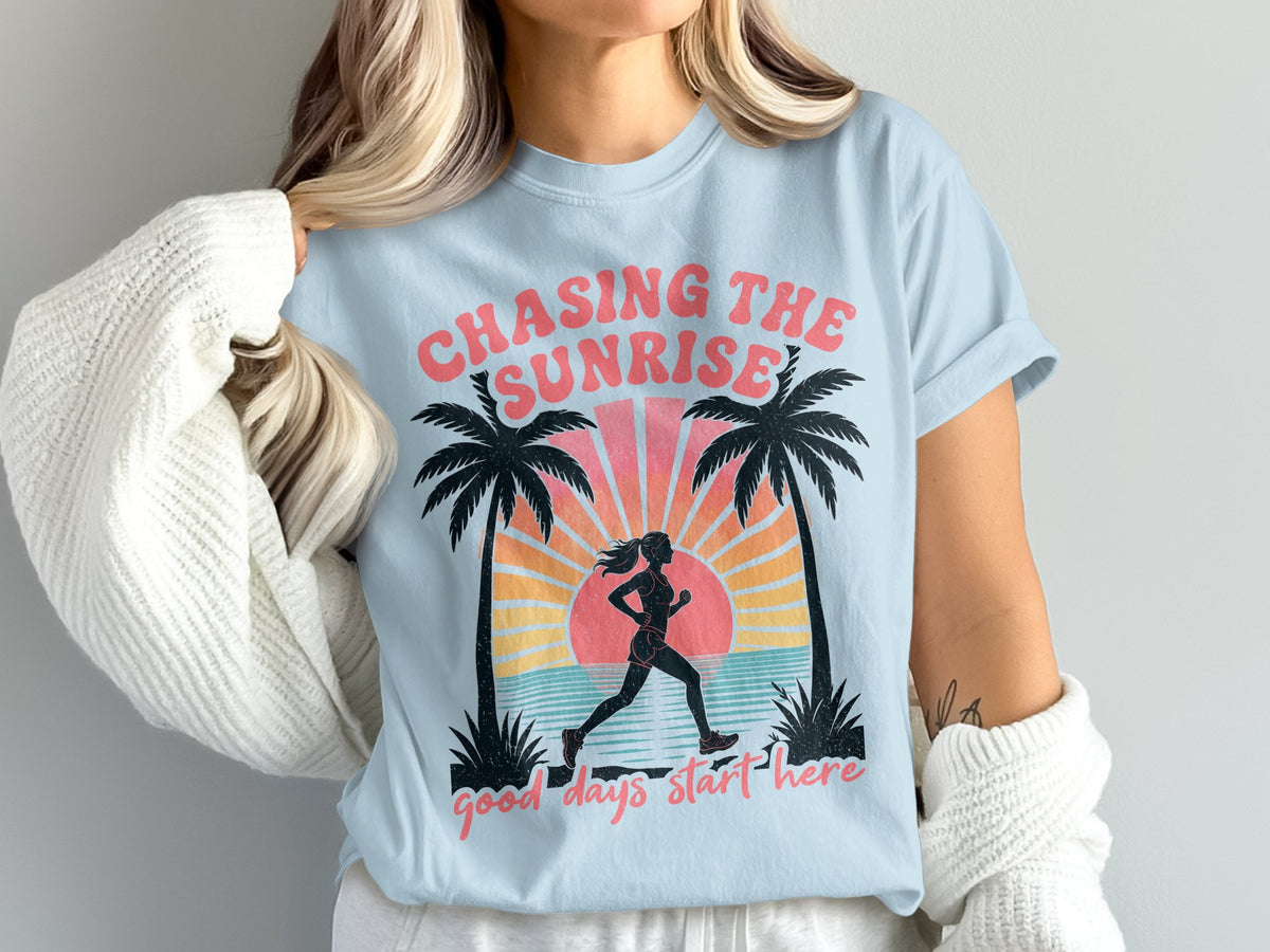 Light blue t-shirt with graphic of runner, palm trees, and text "Chasing the Sunrise" and "good days start here".