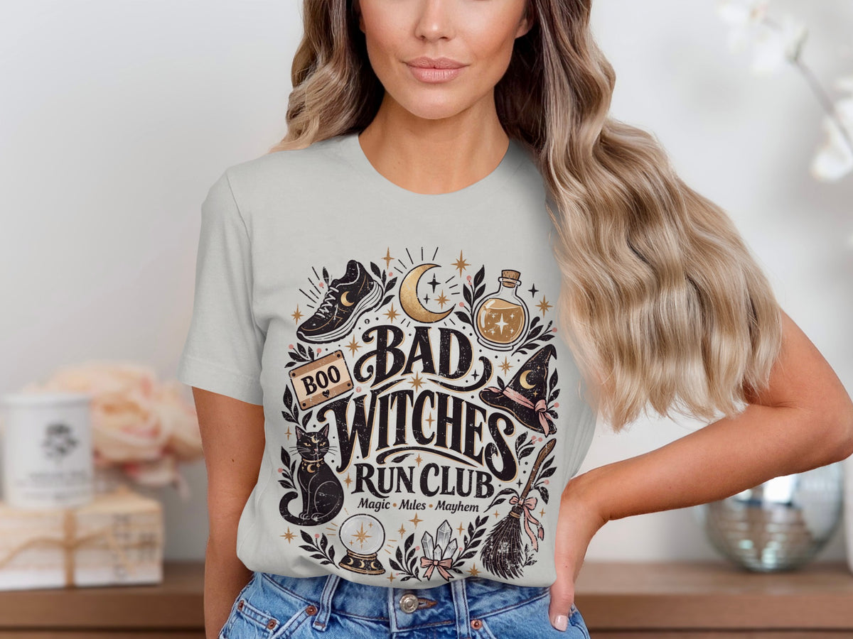 T-shirt graphic with "Bad Witches Run Club" text, black cat, moon, and potion bottle.