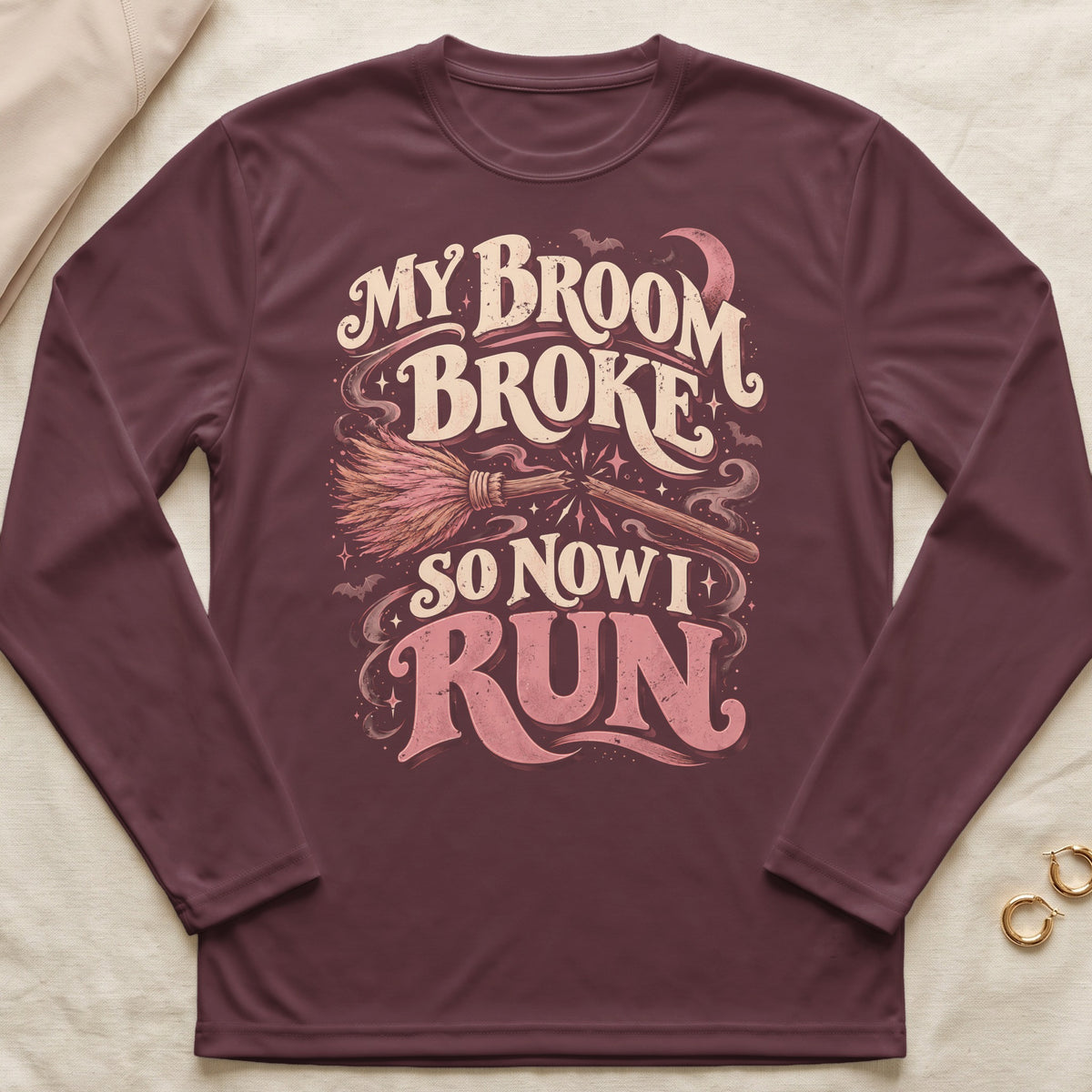 Maroon long-sleeve t-shirt with a graphic of a broken broom and text reading My Broom Broke So Now I Run.