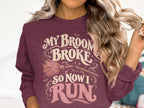 Burgundy sweatshirt with "My broom broke so now I run" text and graphic.