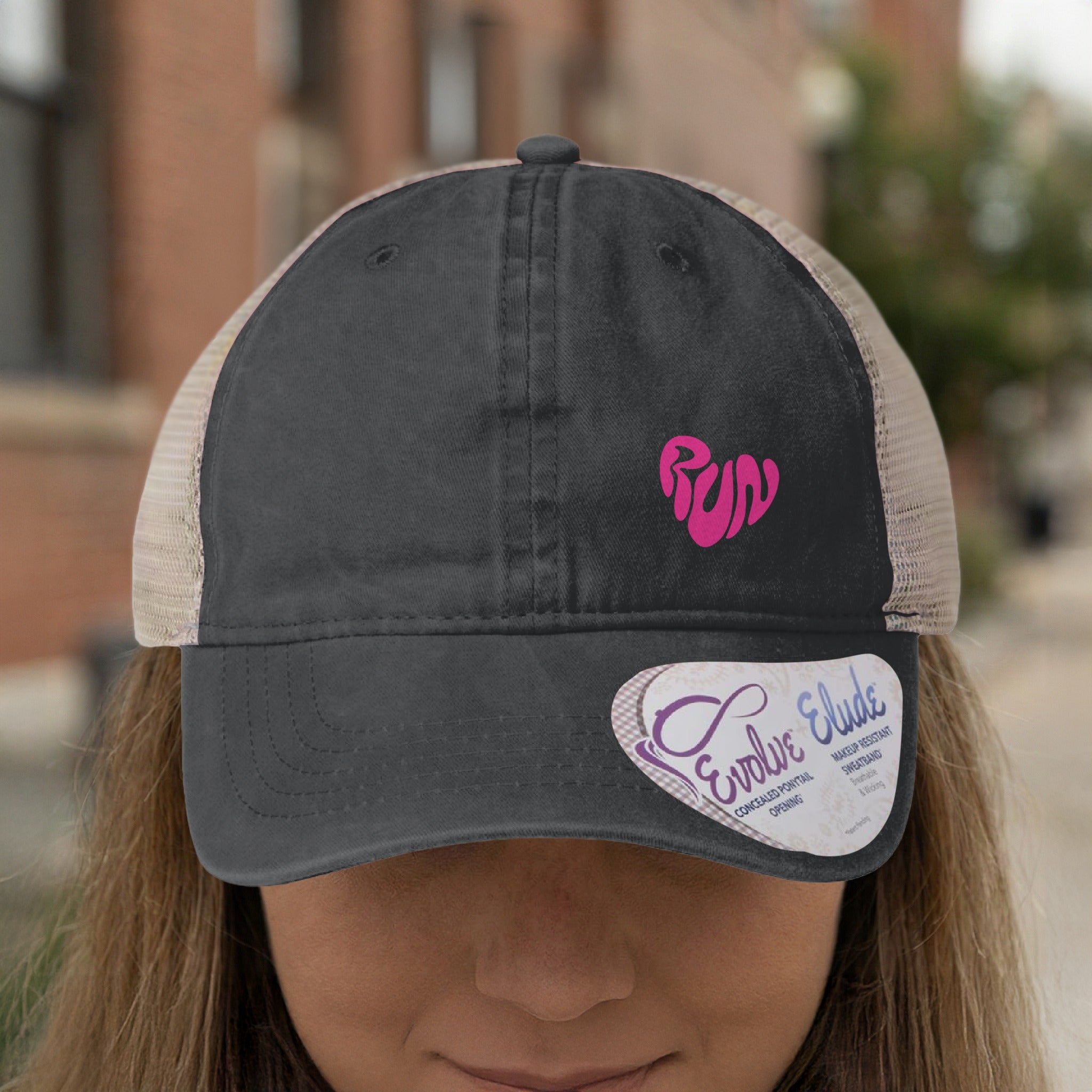 Dark grey trucker hat with pink "run" heart logo and a "Evolve Elude" tag.