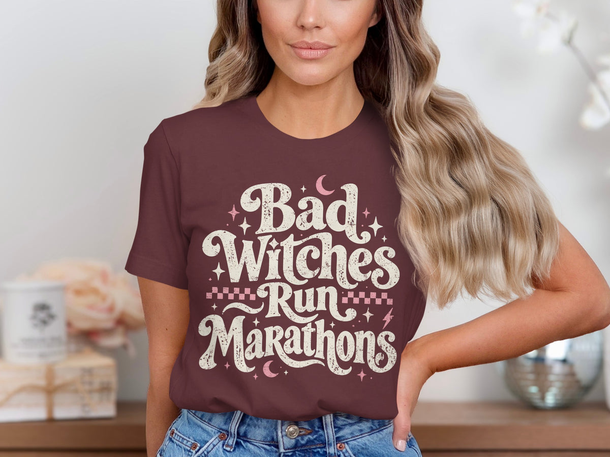 Burgundy t-shirt with distressed text "Bad Witches Run Marathons" and celestial graphics.