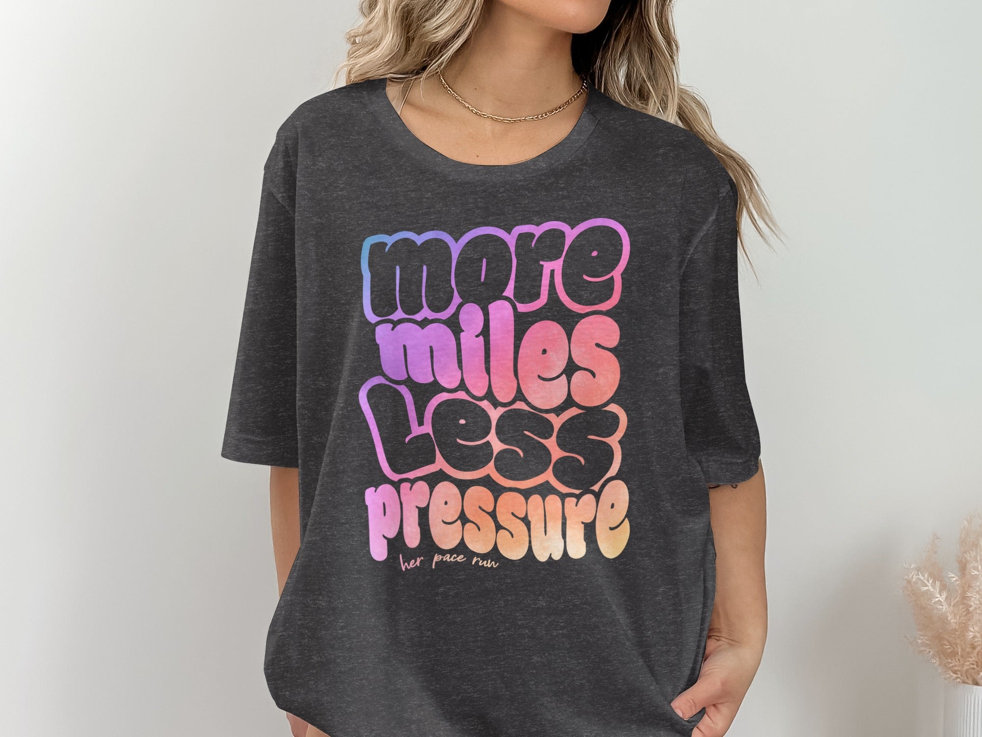 Dark gray t-shirt with "more miles less pressure her pace run" text graphic.