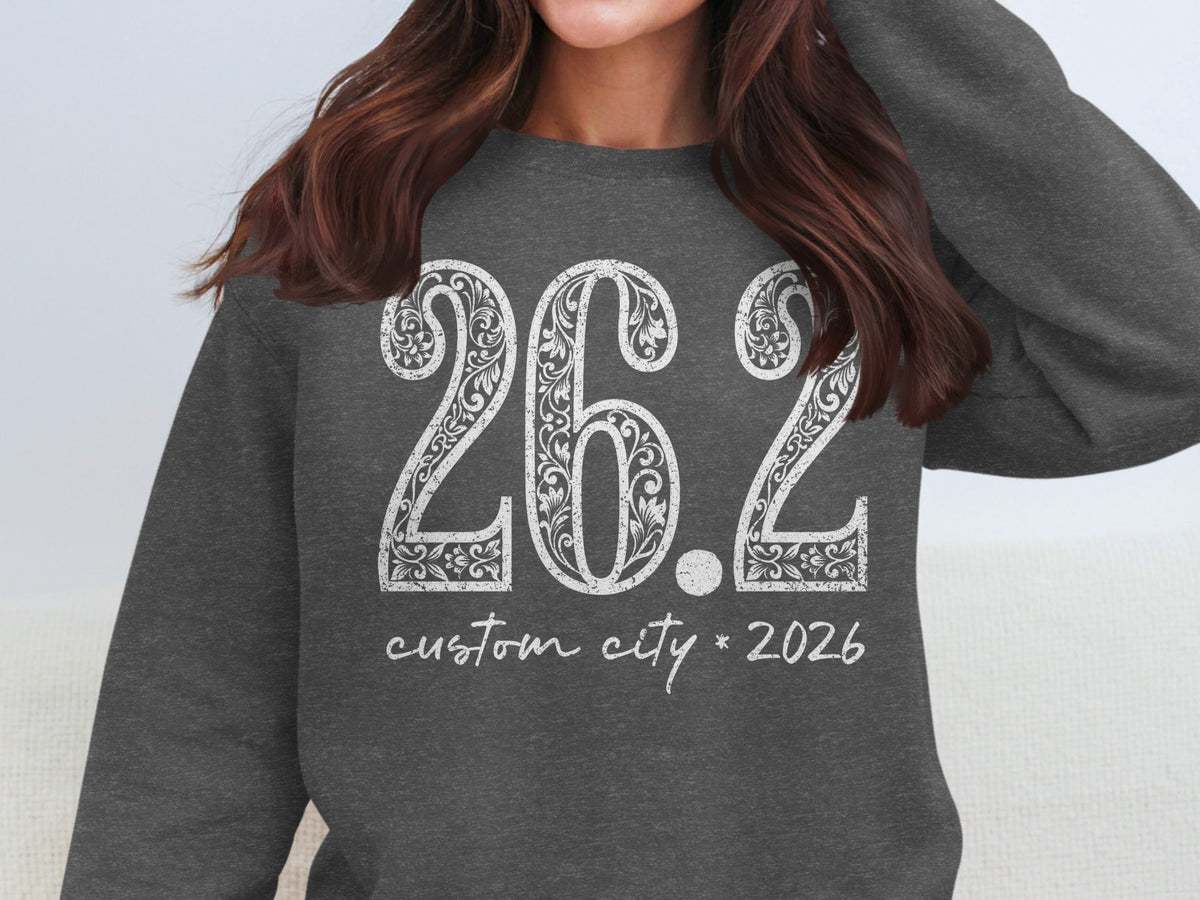 Dark grey sweatshirt with white floral print "26.2 custom city * 2026" design.
