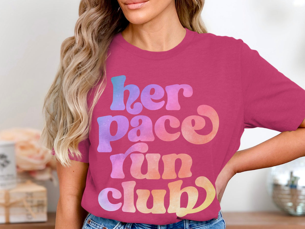 Pink t-shirt with "her pace run club" text in ombre lettering.