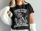 Black t-shirt with skeleton graphic and text: "I asked myself if I'm okay and we both started laughing."