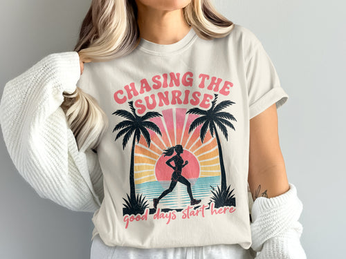 T-shirt graphic with runner, palm trees, sunrise, ocean, and text.