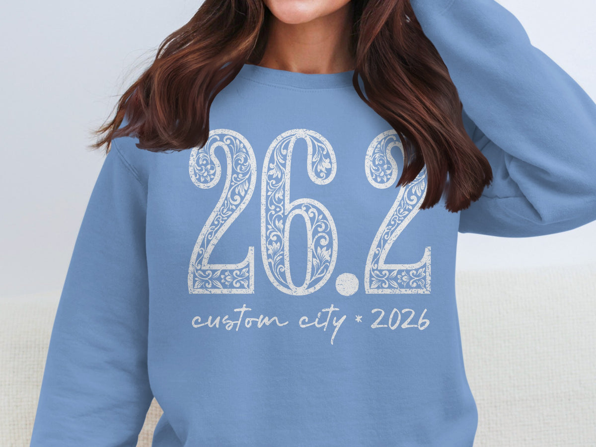 Light blue sweatshirt with white "26.2 custom city * 2026" graphic.