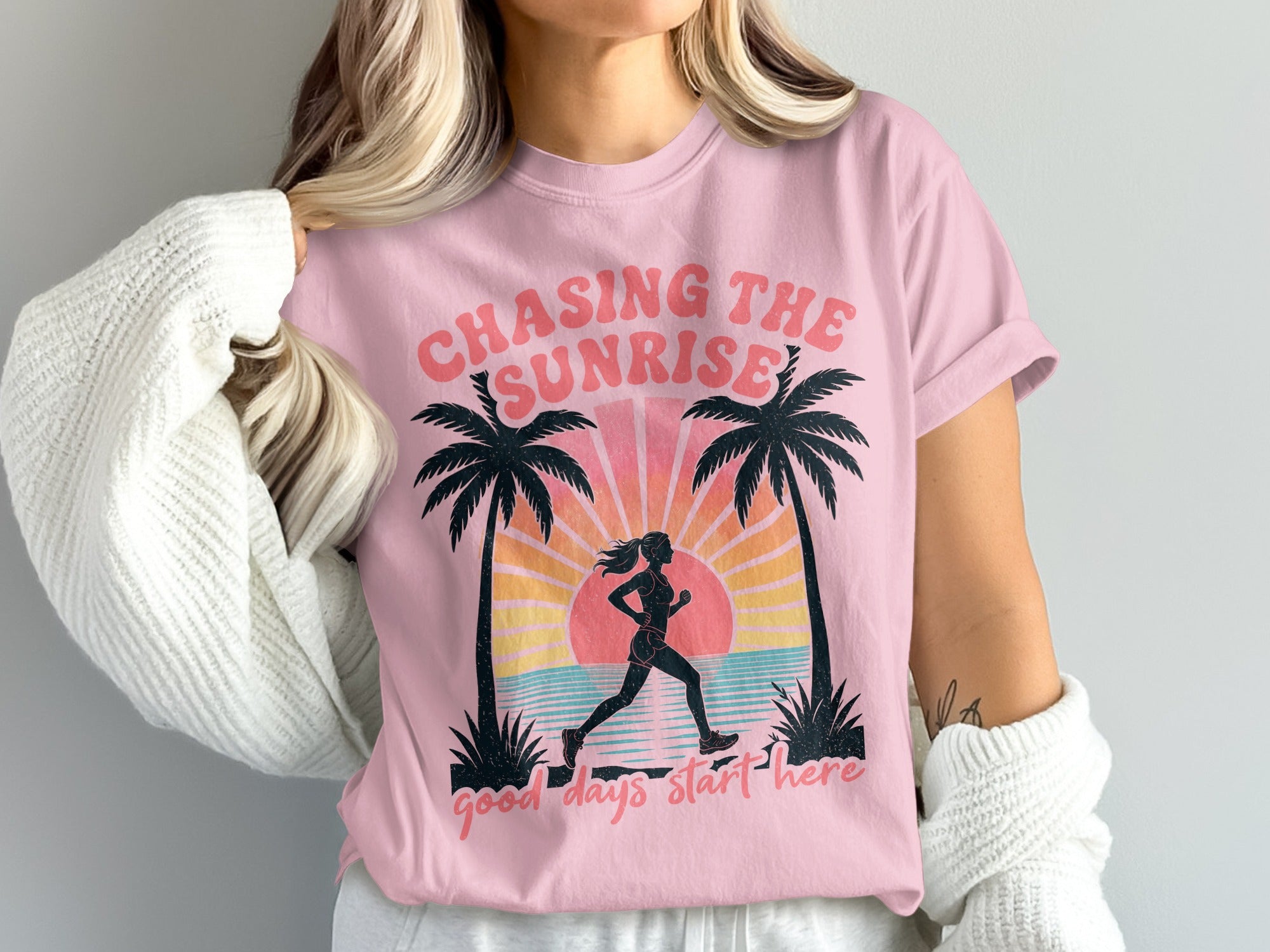 Pink t-shirt with graphic of runner and palm trees at sunrise.