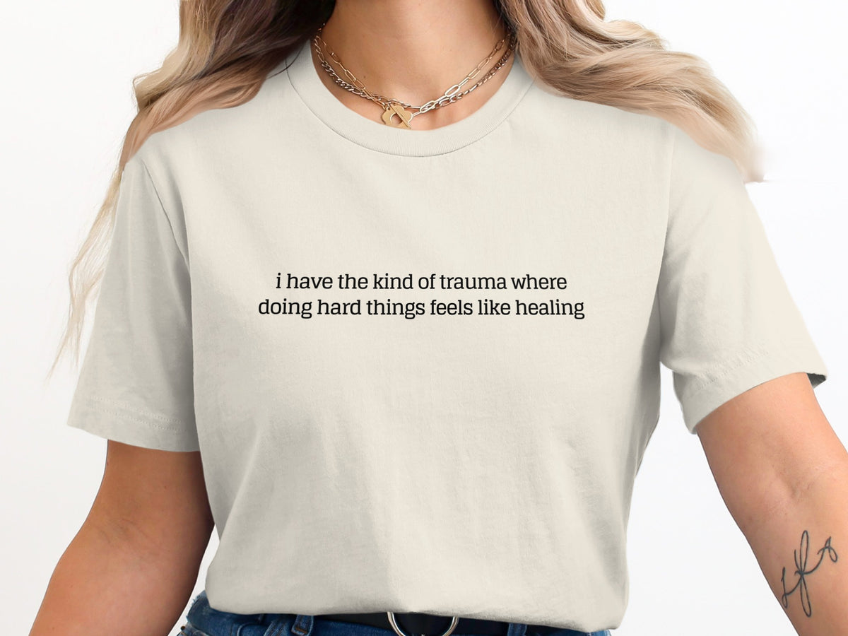 Cream t-shirt with text "i have the kind of trauma where doing hard things feels like healing".