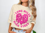 Cream t-shirt with pink text "LONG MILES RUN HIGH VIBES".