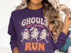 "Ghouls Just Wanna Run" text with three running ghosts on a purple sweatshirt.