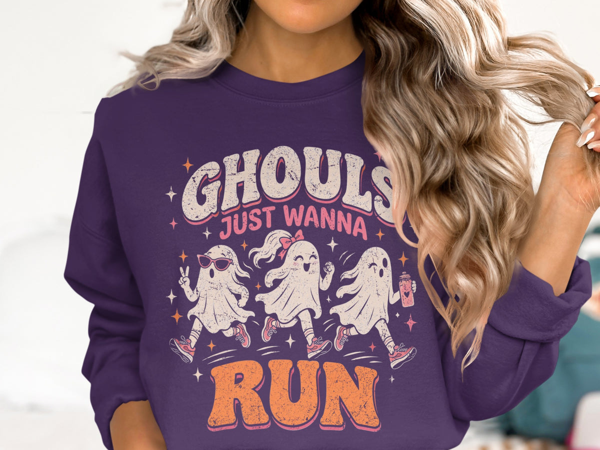 "Ghouls Just Wanna Run" text with three running ghosts on a purple sweatshirt.