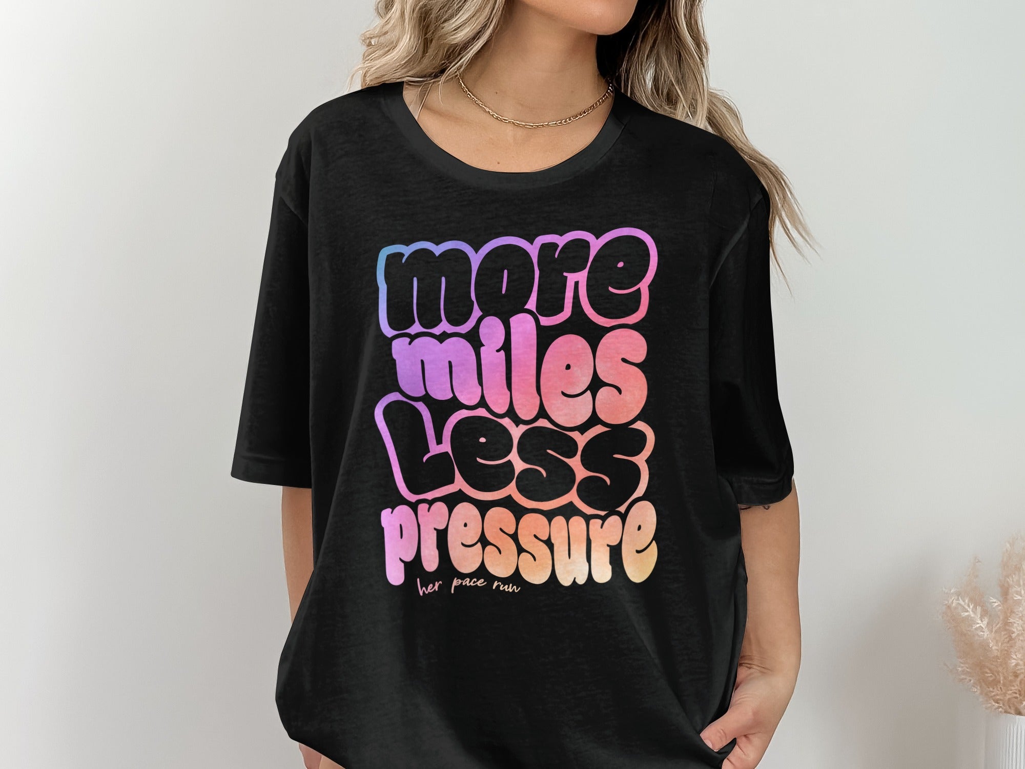 Black t-shirt with "more miles less pressure her pace run" in colorful text.